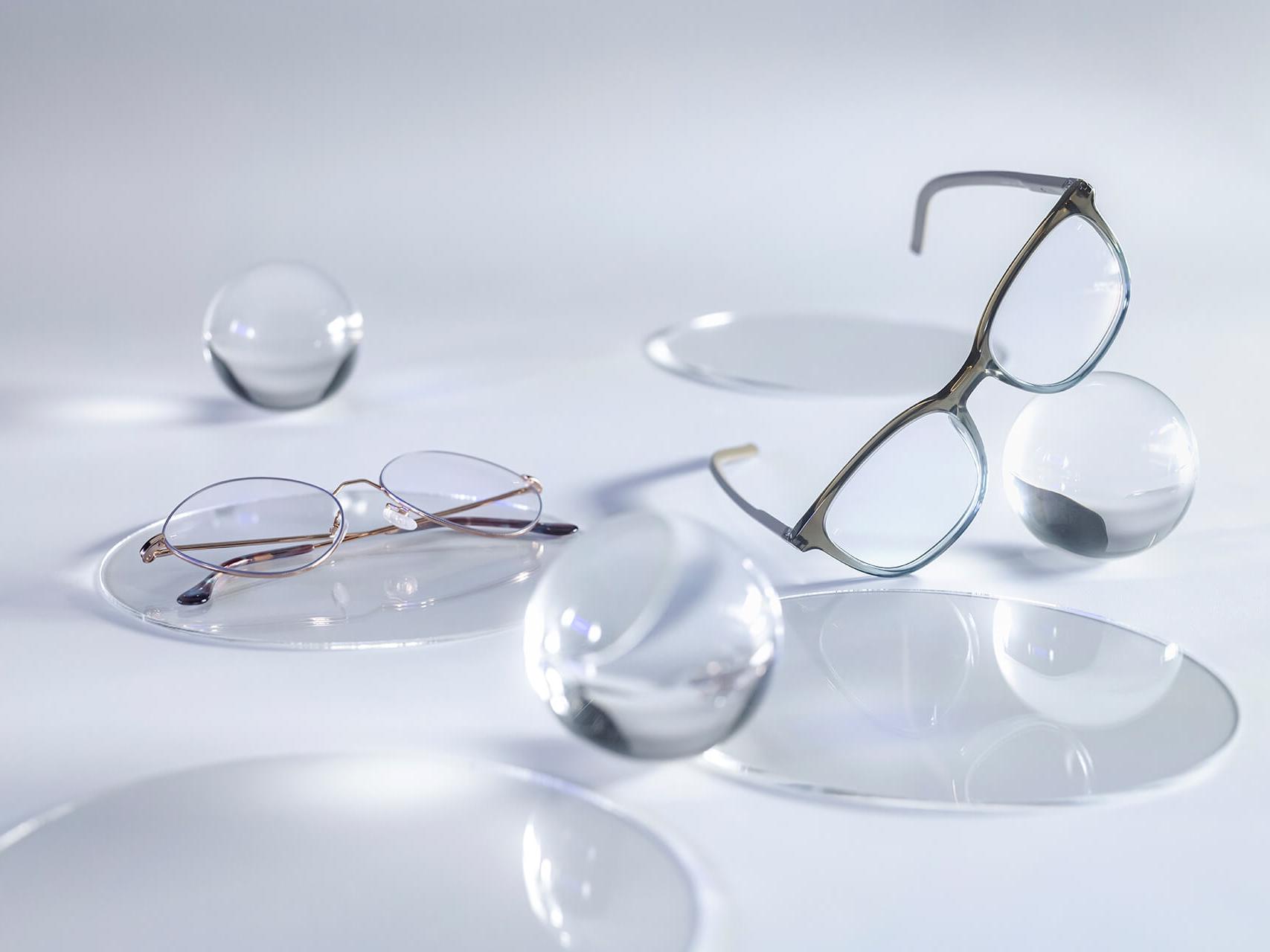 Очила с лещи ZEISS с покритие DuraVision® Silver, които не отразяват светлината в сравнение с околните стъклени сфери.