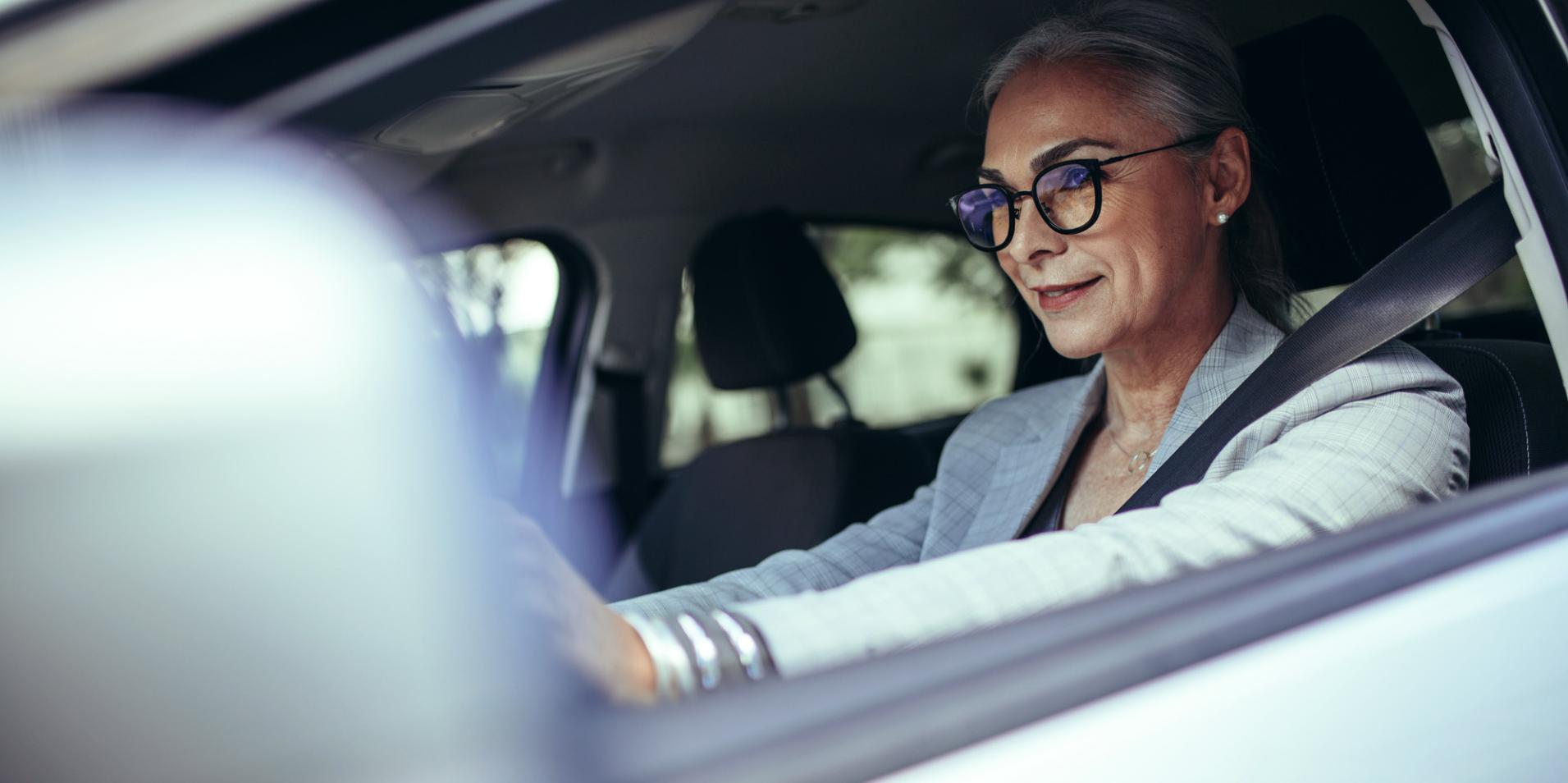 Жена на зряла възраст в кола, носеща очила с лещи ZEISS DriveSafe.