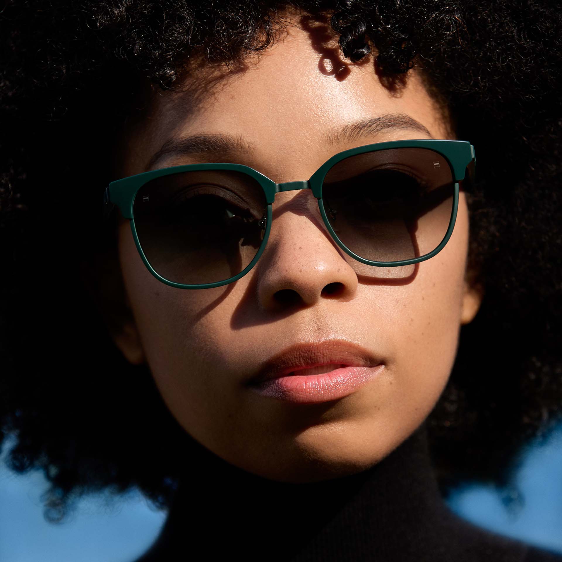 Жена, носеща очила със зелена рамка и стъкла с градиентен (преливащ се) нюанс. 