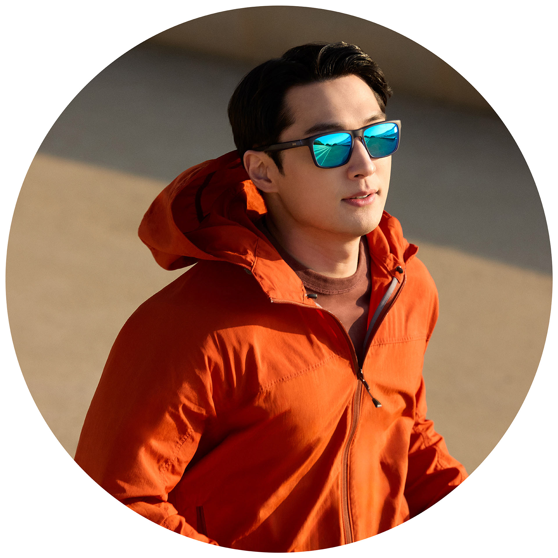 Бегач с оранжево яке, носещ слънчеви диоптрични очила на ZEISS със синьо огледално покритие.