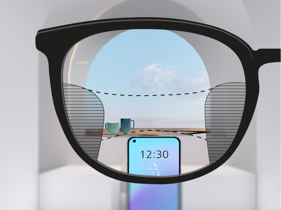 Изображение от гледната точка с лещите ZEISS Progressive SmartLife със смартфон и чаши на заден план, докато лещата е напълно ясна с тънки размазани участъци вляво и вдясно.
