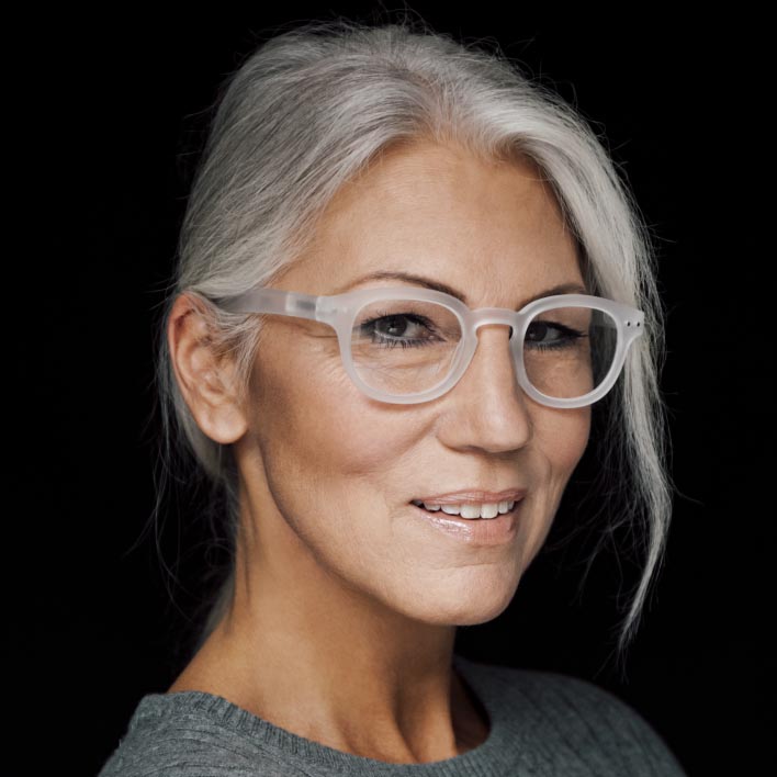 Жена с посивяла коса с бяла рамка с прогресивни лещи ZEISS SmartLife Progressive. Геометрично сканиране на лицето, показващо анатомията на лицето и измерванията на рамката.